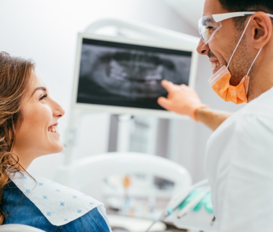 A dentist uses dental IT support technology while speaking with a patient